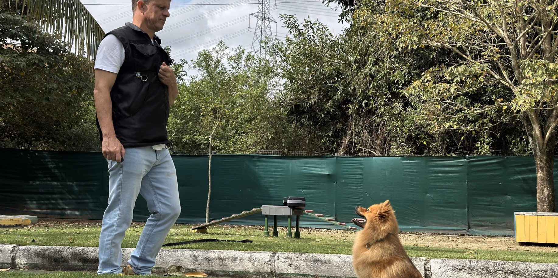 Adestrador caminhando na guia com um cão de pequeno porte ao lado — adestramento de cães em Copacabana