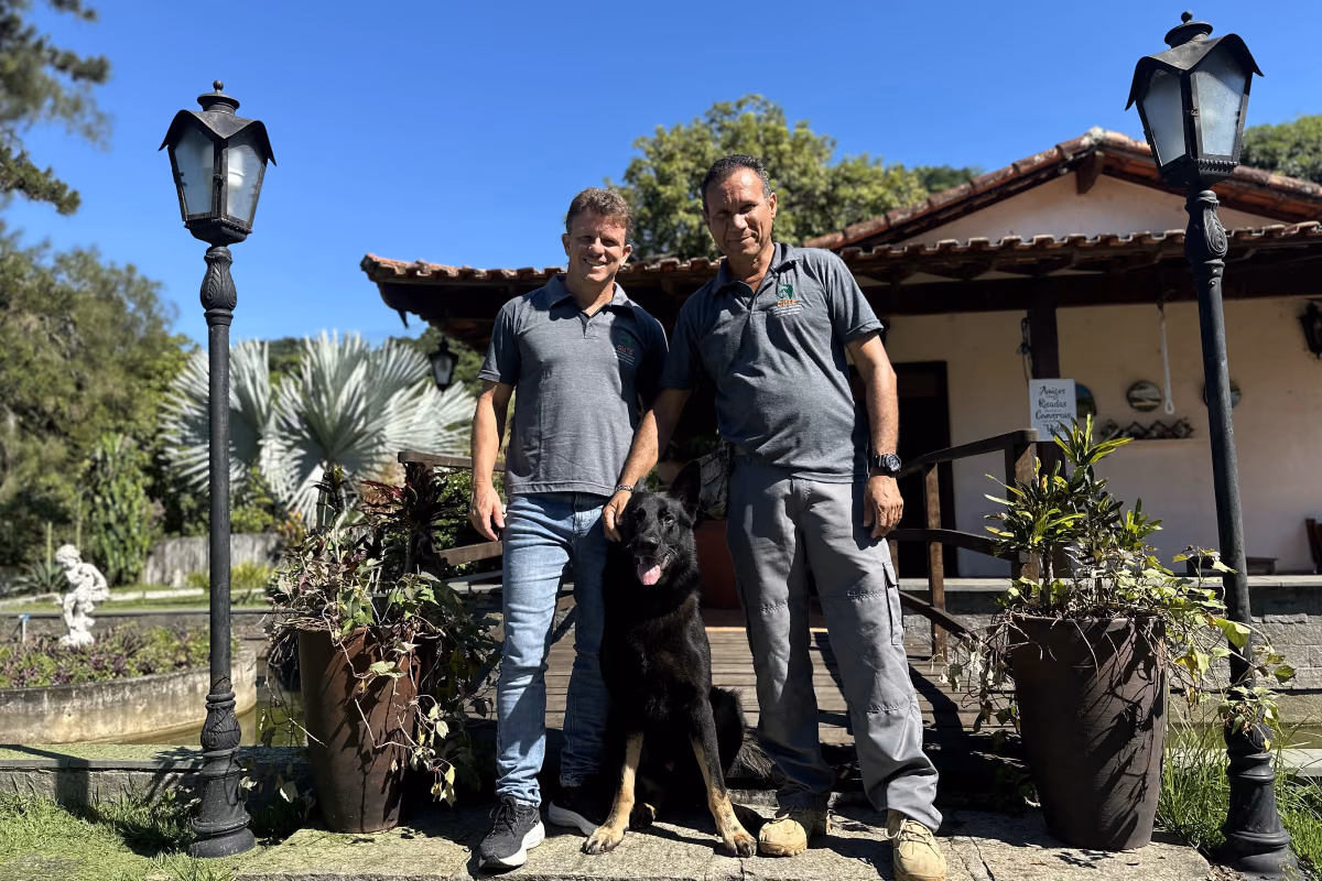 Idade para castrar cachorro: quando fazer e o que considerar Cão de grande porte com dois integrantes da equipe em frente a uma casa