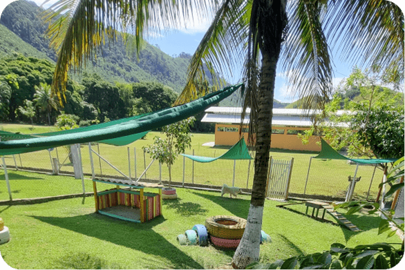 Área verde do Gute Hotel com jardim, redes e montanhas ao fundo